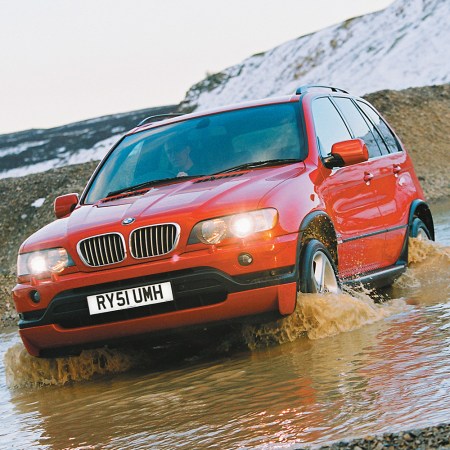 An early BMW X5 driving through deep water in the wilderness. We take a look at the history of the BMW X series.