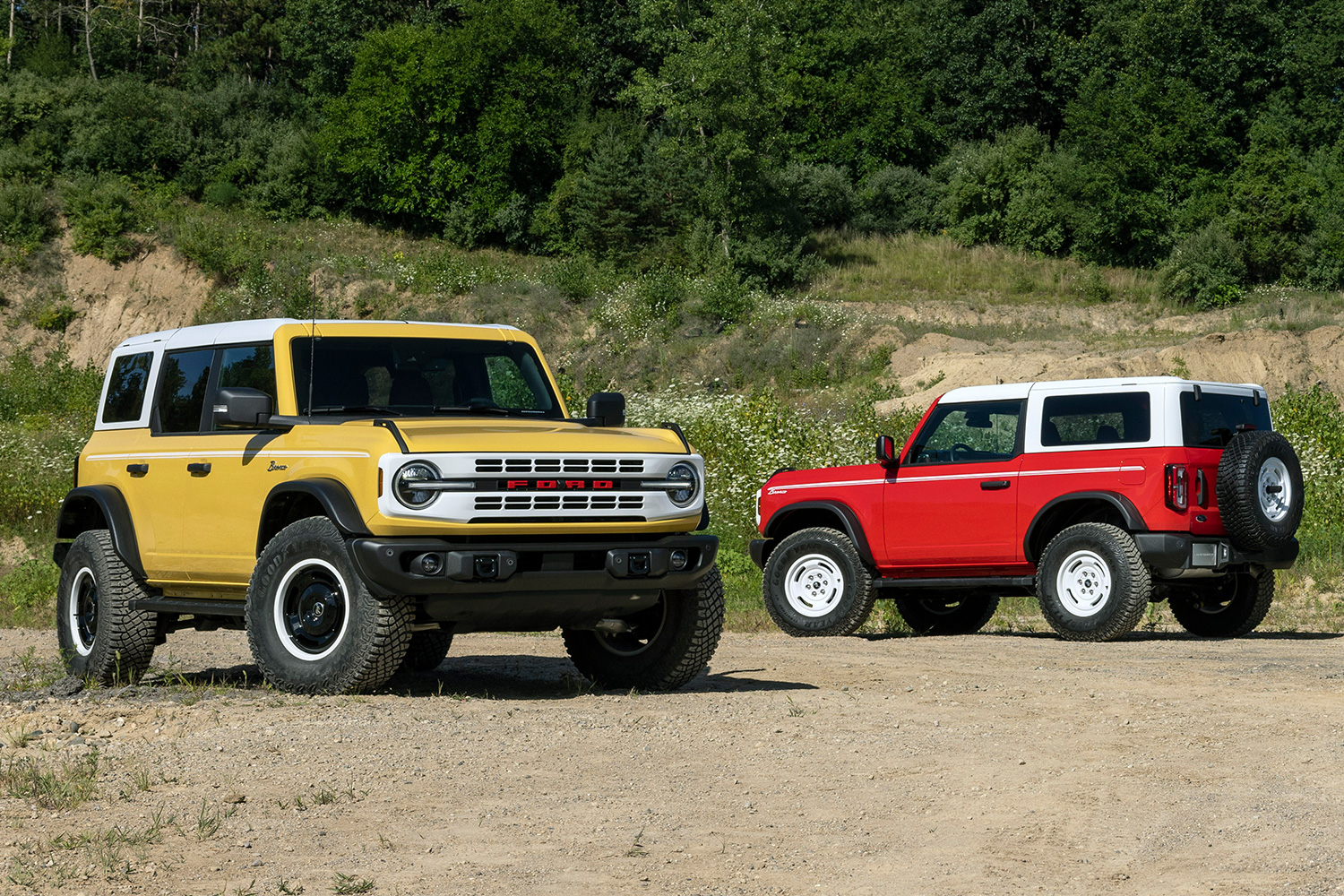 Two Ford Bronco Heritage Edition models, one in yellow and one in red, both with white tops