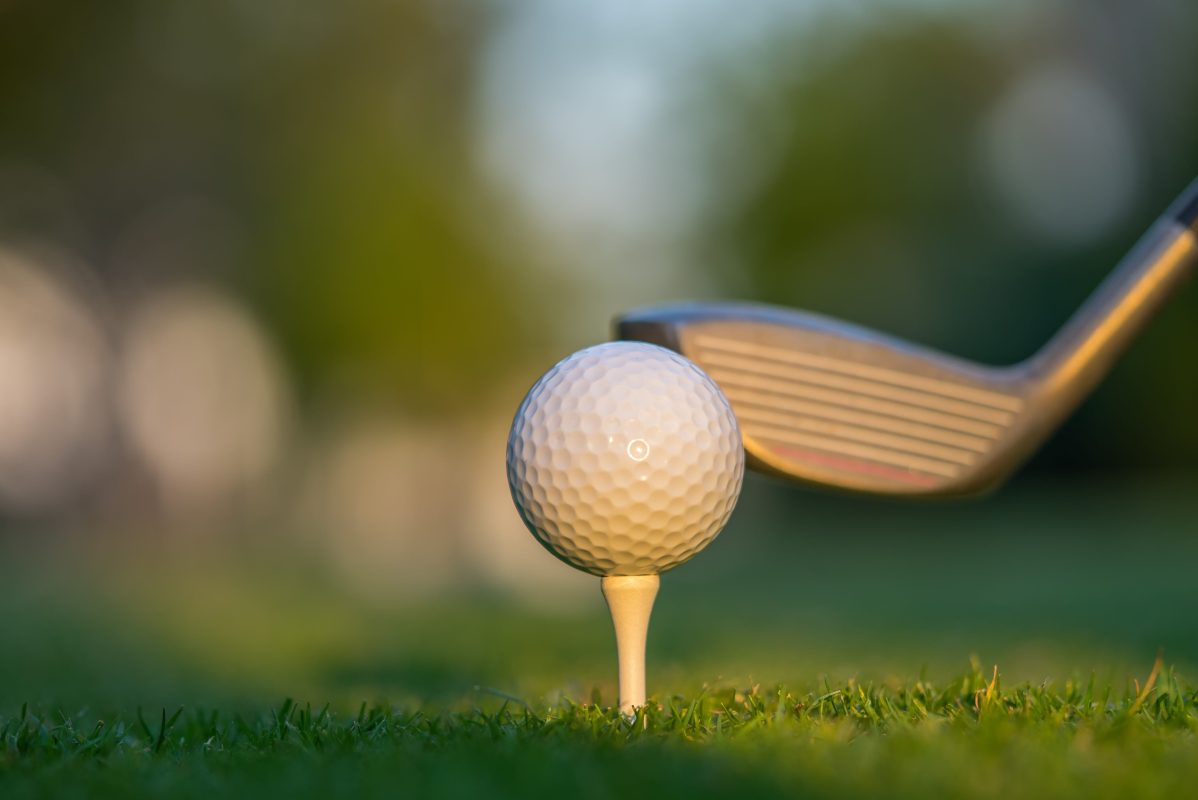 A golf ball on green grass ready to be struck.