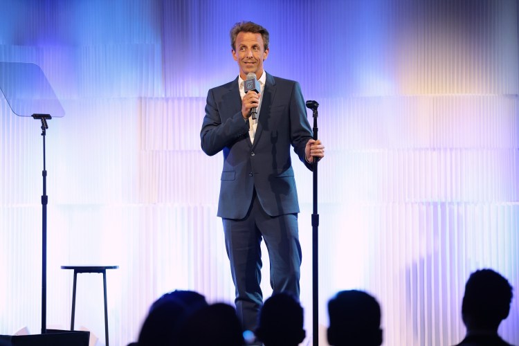 Seth Meyers on stage holding a mic
