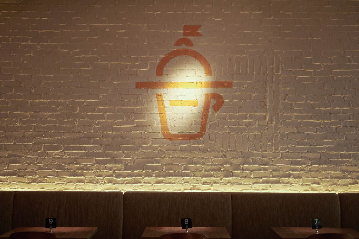 yellow coffee graphic on a white brick wall