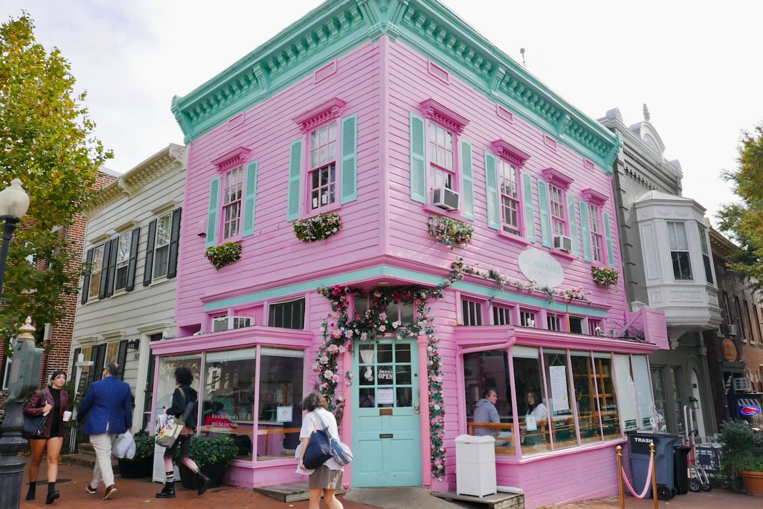 Bright pink building with light blue and teal-green accents on the corner of a street