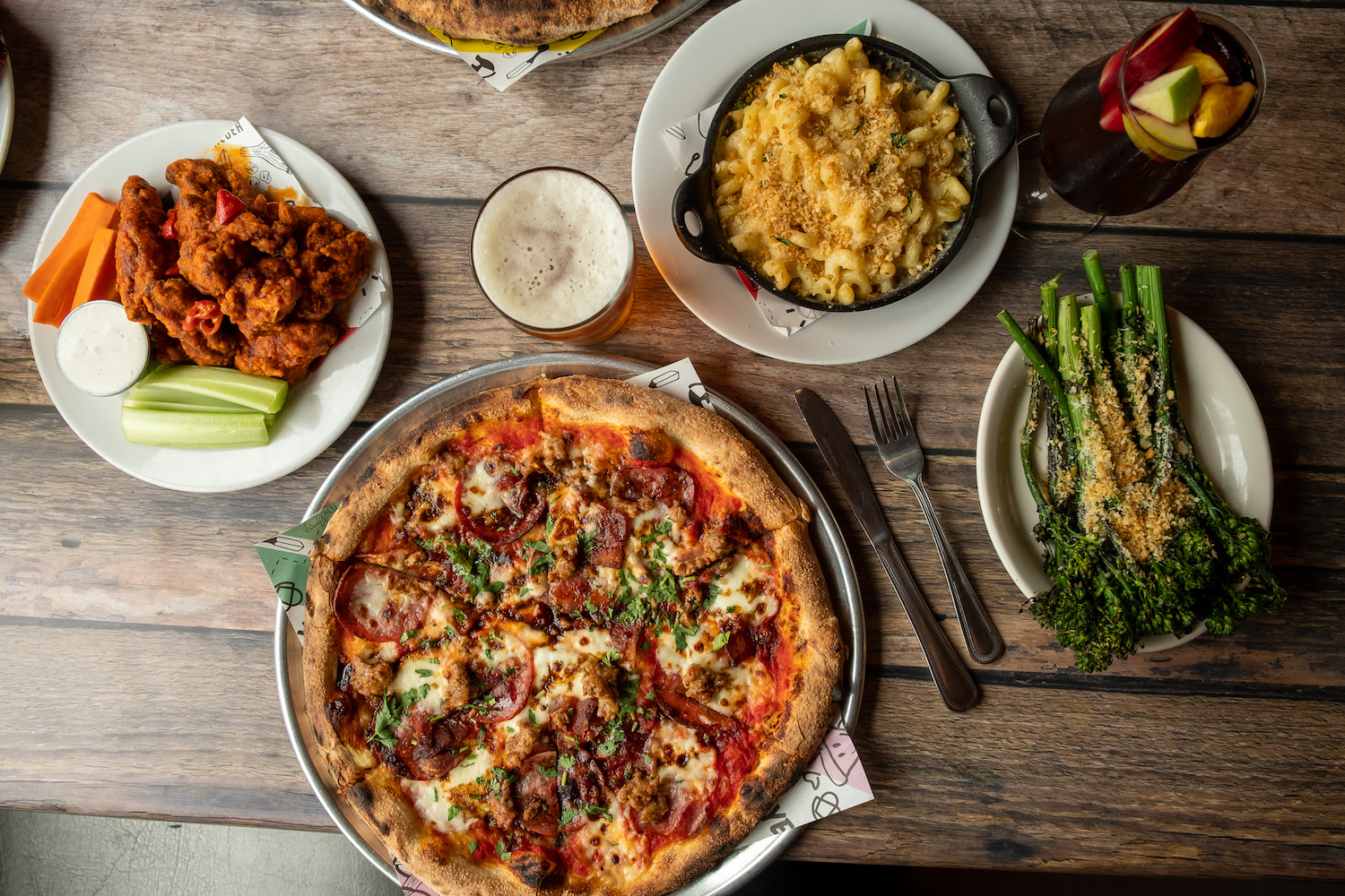 Birds-eye view of pizza, broccoli florets, mac and cheese and wings on a table