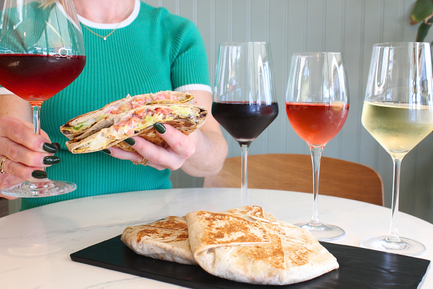 Crunchwrap Supremes on a plate with wine glasses filled with wine 