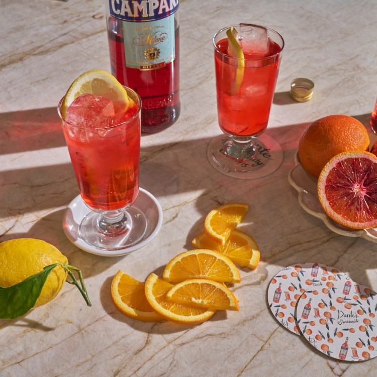 Beverages in glasses surrounding a bottle of Campari and other garnishes