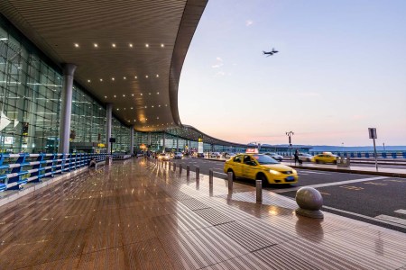 Cars pulling up outside an airport terminal. We look at the first Enrollment on Departure option opening, which could revolutionize the Global Entry process.