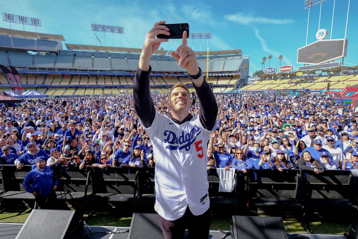 Person taking a photo with a crowd in a Dodgers shirt in Dodgers stadium