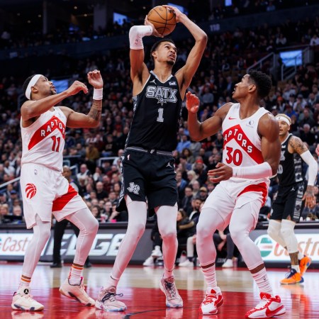 Victor Wembanyama (Wemby) of the San Antonio Spurs looks to the basket as he's defended by Bruce Brown #11 and Ochai Agbaji #30 of the Toronto Raptors in an NBA game on February 12, 2024