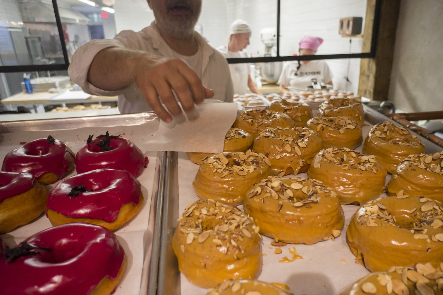 An employee at Dough bakery in the Flatiron neighborhood of New York serves a dulce de leche doughnut to a visitor