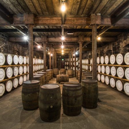 stacked wooden barrels inside a distillery