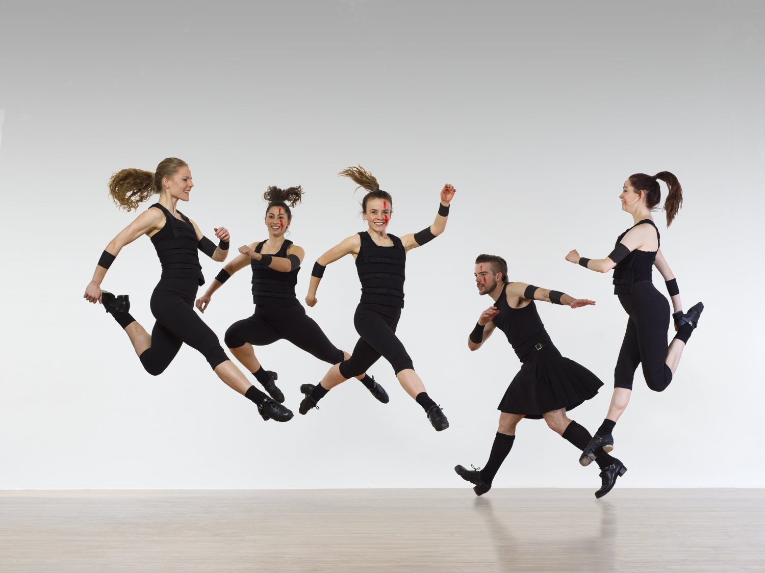 dancers jumping in mid air in black clothes and face paint
