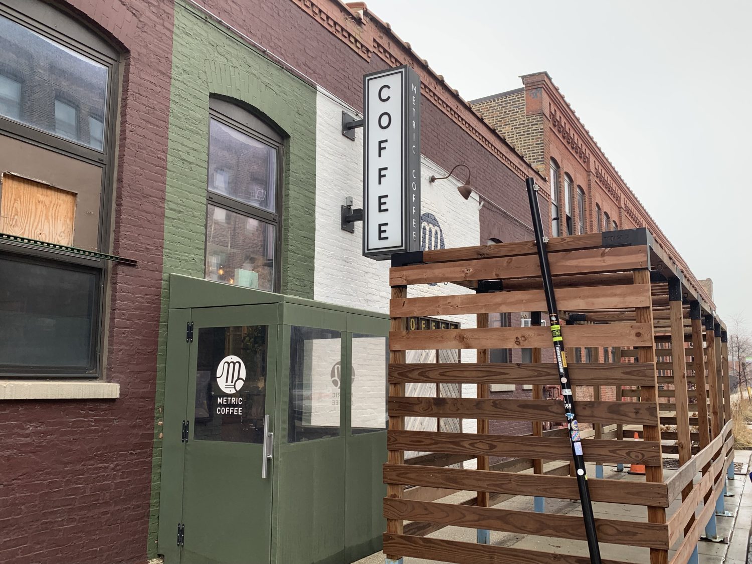 brick building green paint on wall, coffee sign mounted on wall, wooden crate 