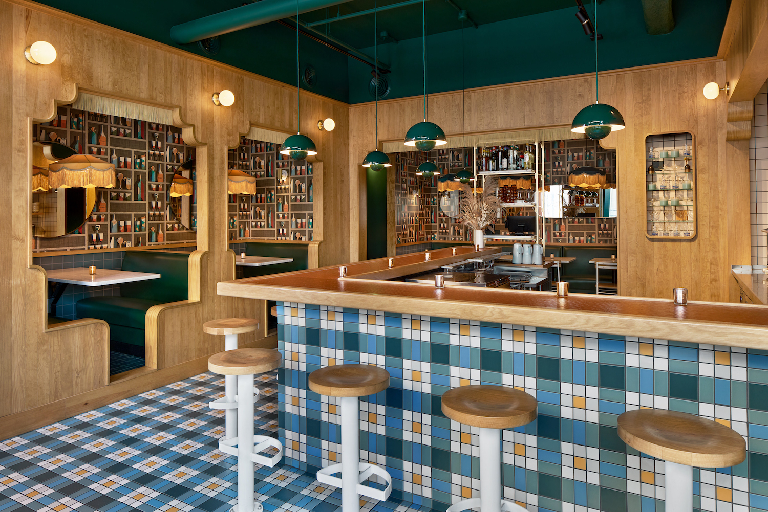 Indoor dining area with a bar and in-the-wall booth seats. There's blue-and-white-checkered floor patterns and cocktail glass wallpaper