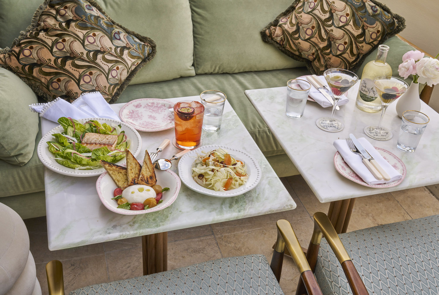 Two tables in front of a light green couch with small plates and cocktails