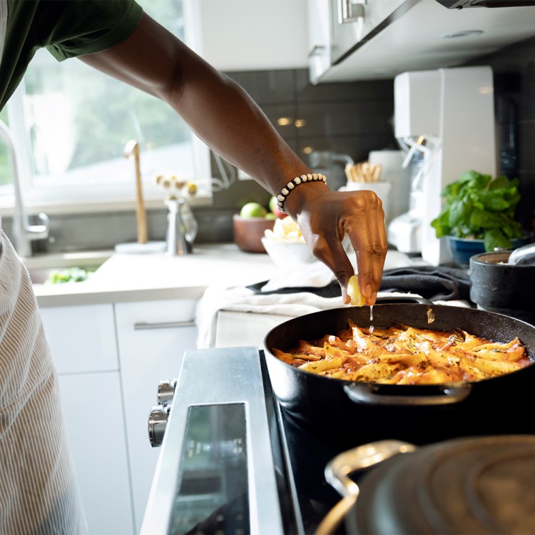 A man seasoning food in a pan. Today we break down some easy nutrition advice: making one home-cooked meal a week.