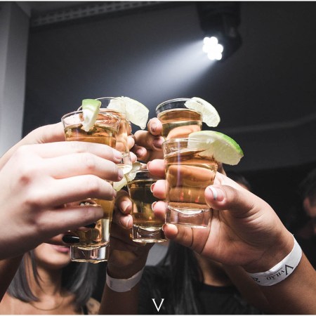 Several hands cheers-ing with tequila shots. The tequila industry saw a surprising decrease in 2023.