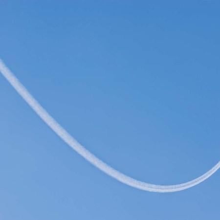 An airplane flying with a contrail being produced behind it
