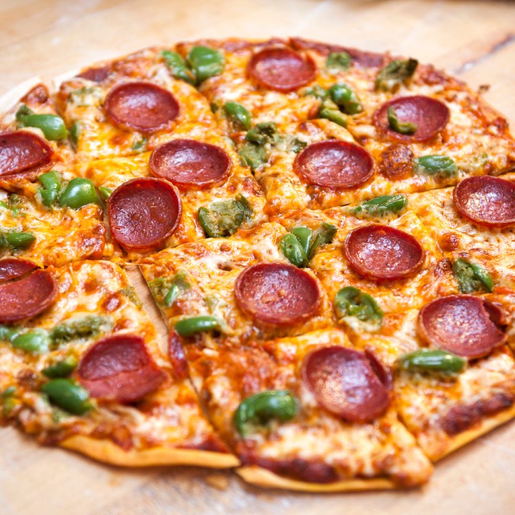 A square cut, thin crust, pepperoni and green pepper cheese pizza on a butcher block surface