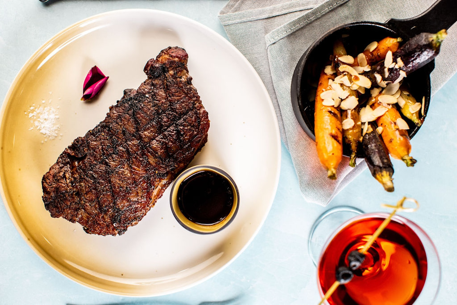steak with sauce on the side and a flower petal on a plate, cocktail, squash with nuts, 