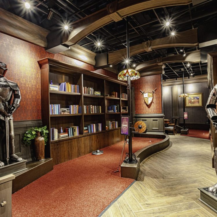 two knight statues in armor, mini golf, red carpet, book shelves with books, lamps