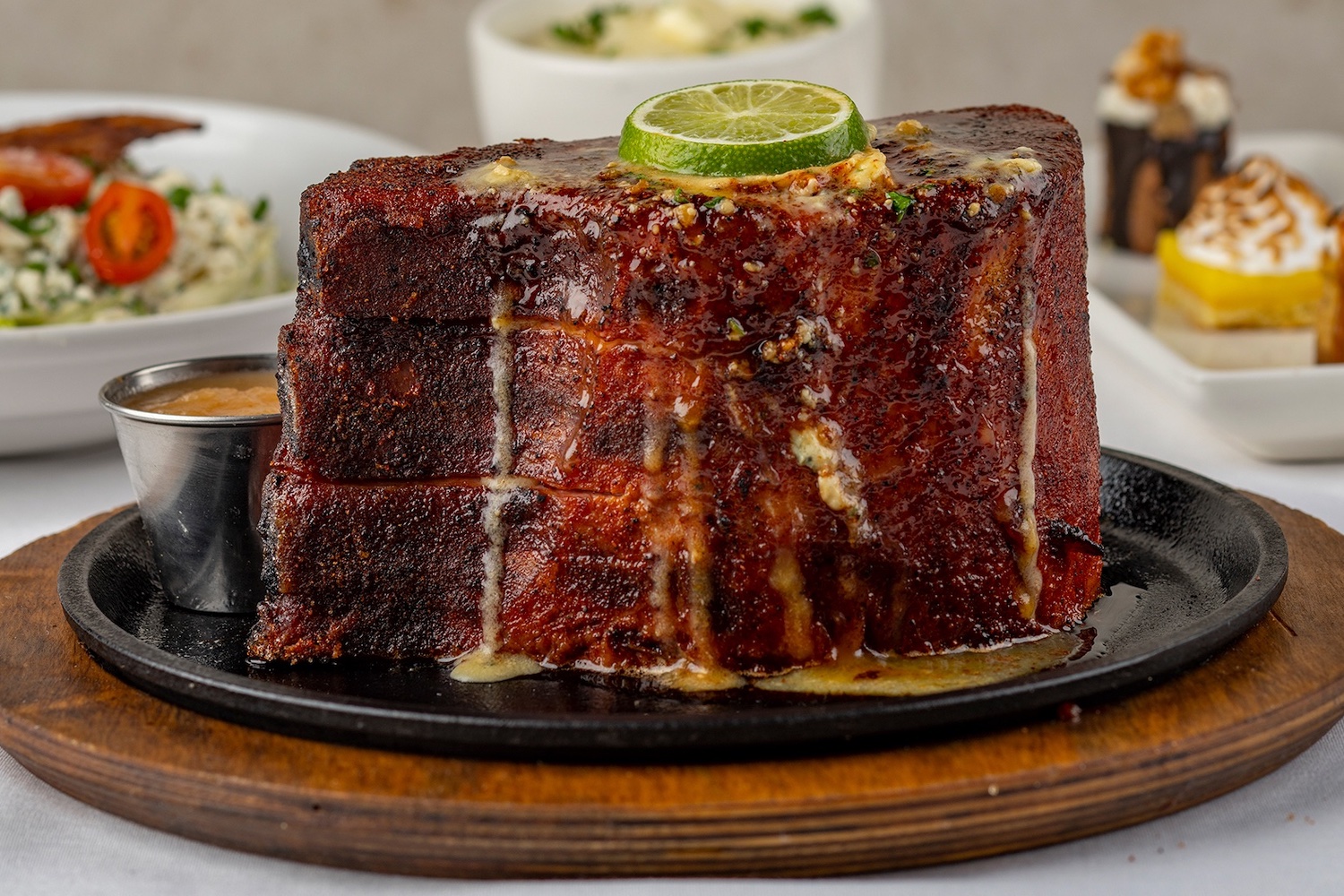 a massive and tall port chop topped with lime and butter sitting on a cast iron plate