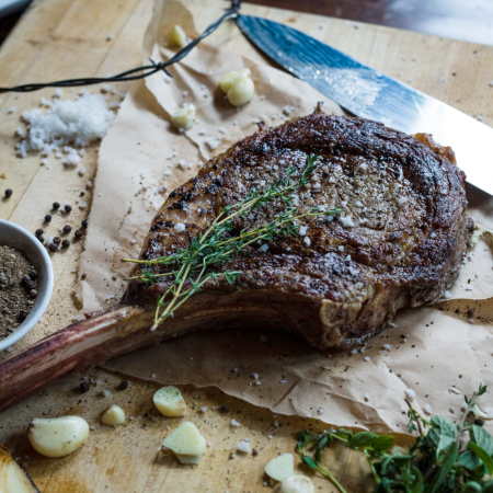 steak with herbs on paper, spices and garlic on table, steak knife