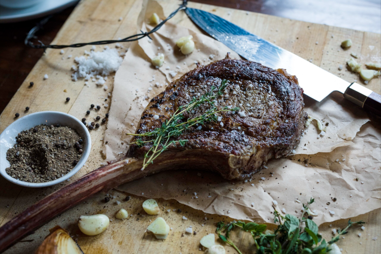 steak with herbs on paper, spices and garlic on table, steak knife