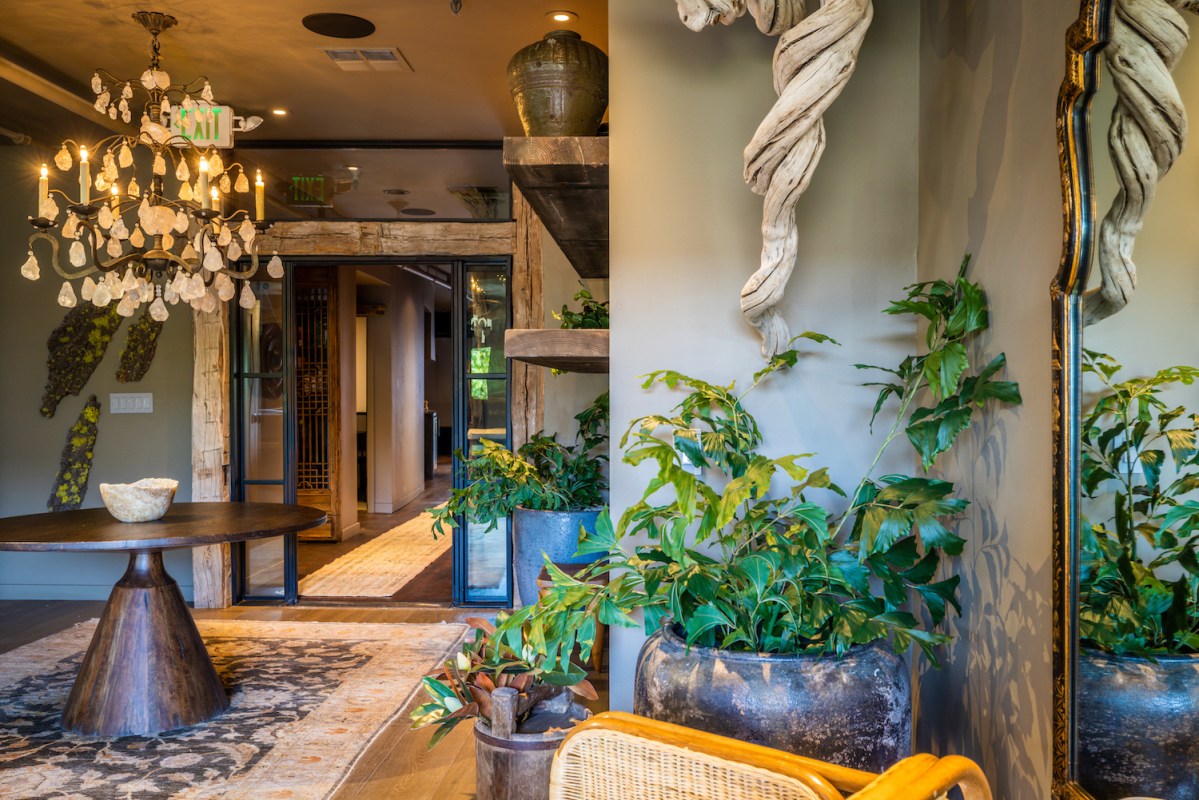 an entrance to a spa with plants, wooden beams and stone accents