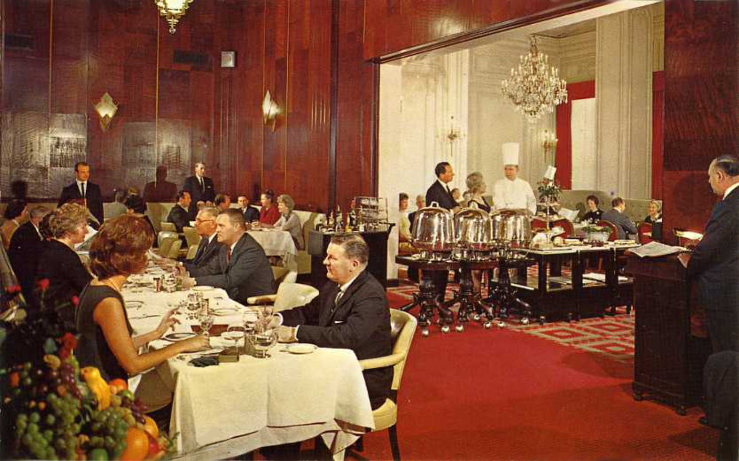 people having dinner, wooden walls, chandeliers, food on plates and glasses