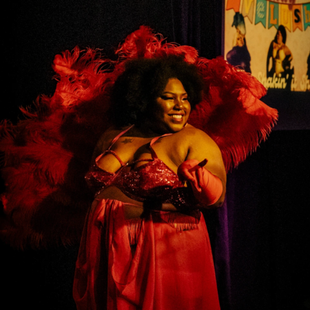 women in red dress and red feather boa behind her