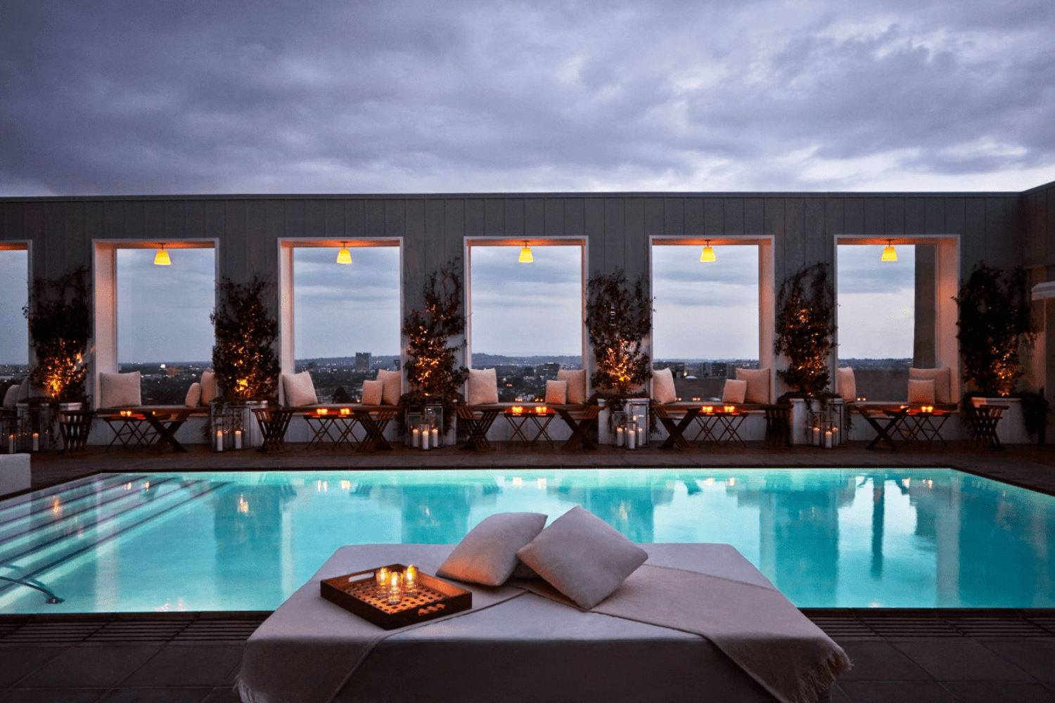 pool at twilight, beds and chairs with candles on them 