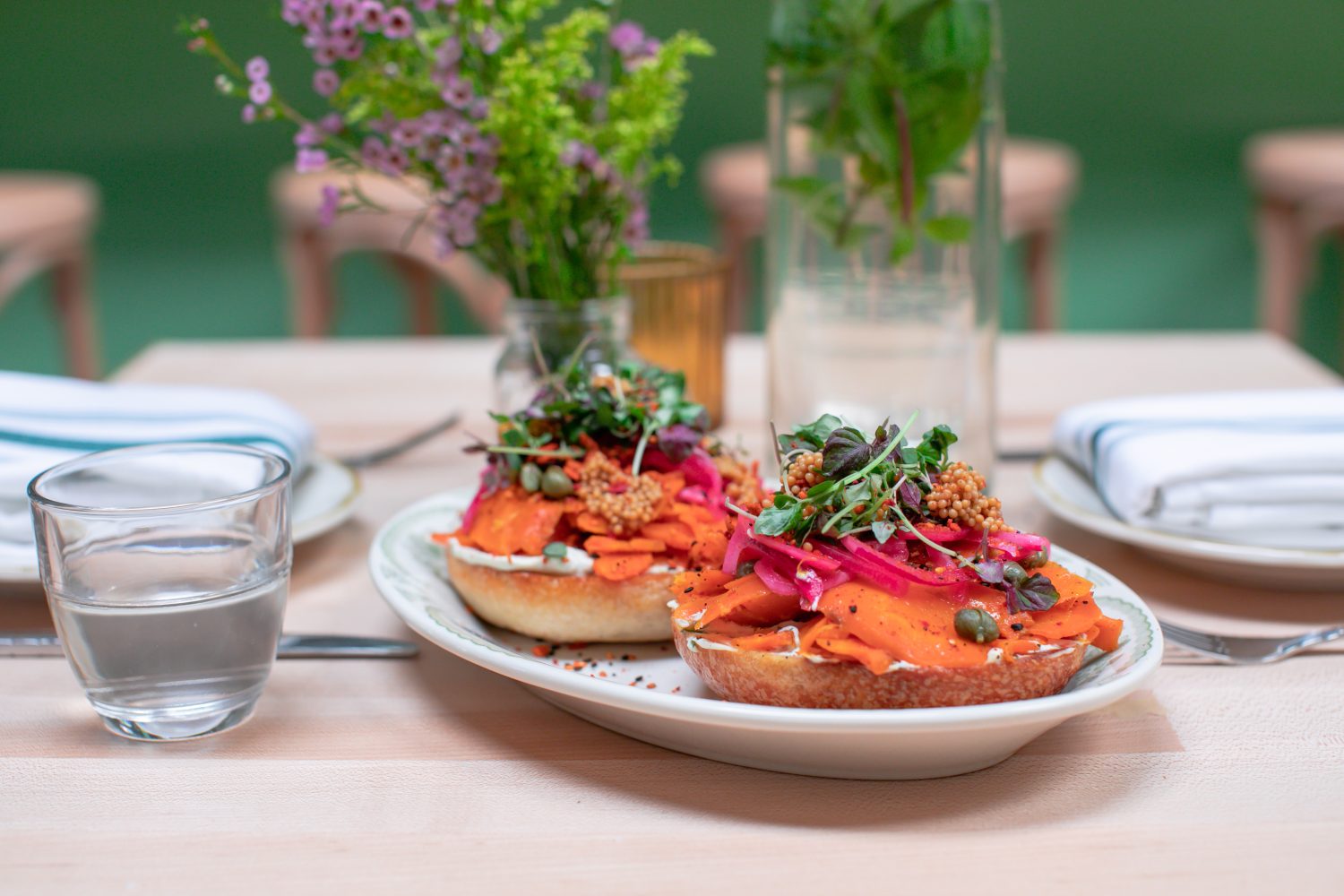 bagels with lox and capers on a white plate, plant on the table