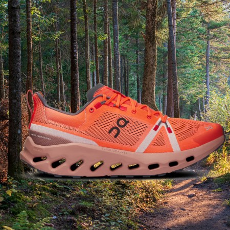 The On Cloudsurfer Trail, a trail-running shoe, against a forest background. Here's our full review of the shoes.