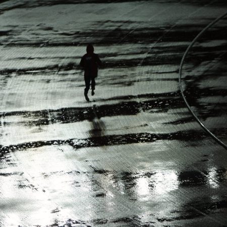 A man running on a rainy track at night.