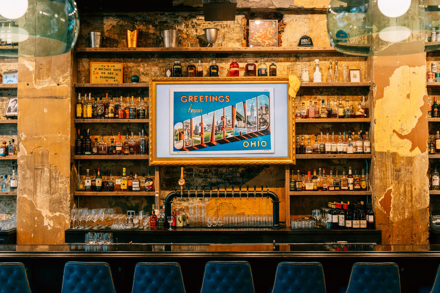 a bar with a sign hanging over the bottles that reads welcome to cleveland