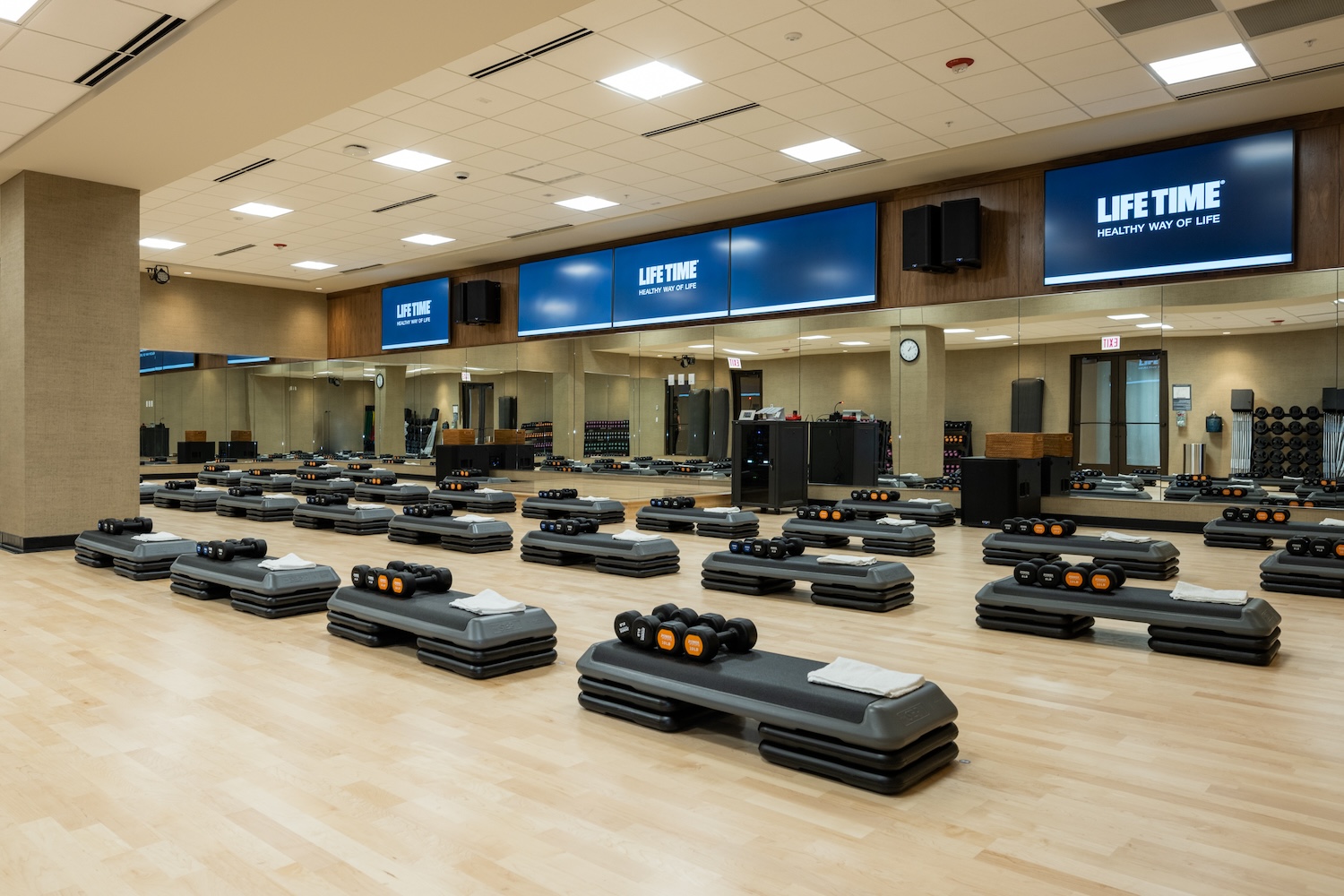 weights on machines on a wooden floor, tvs hanging, speakers, mirrors