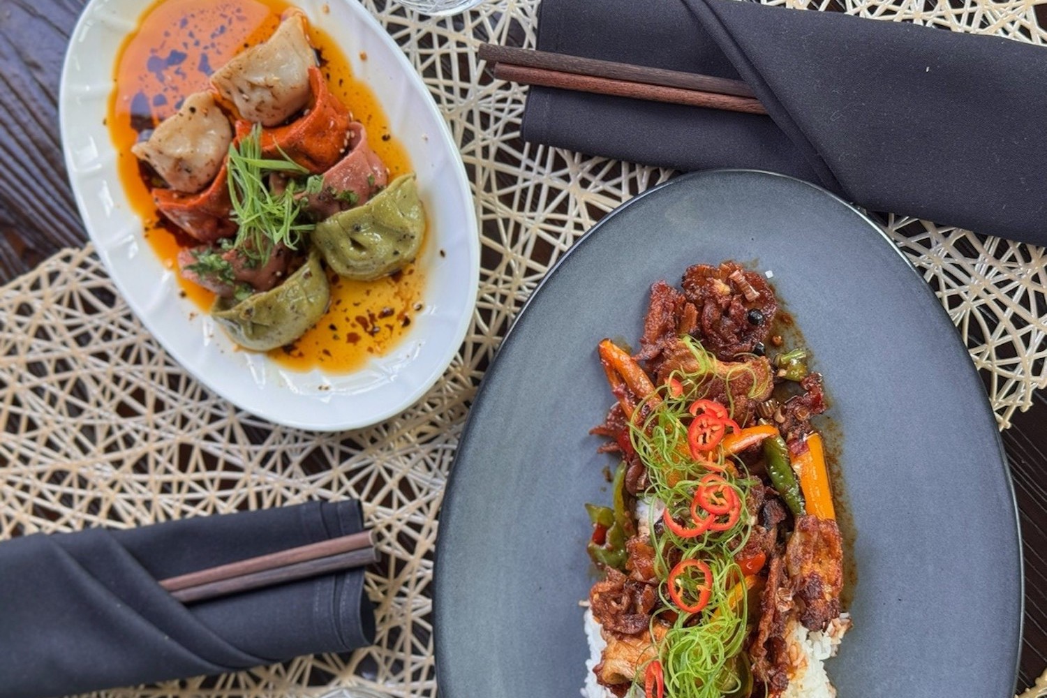 chinese dumplings and a beef and rice dish on a table with navy blue napkins