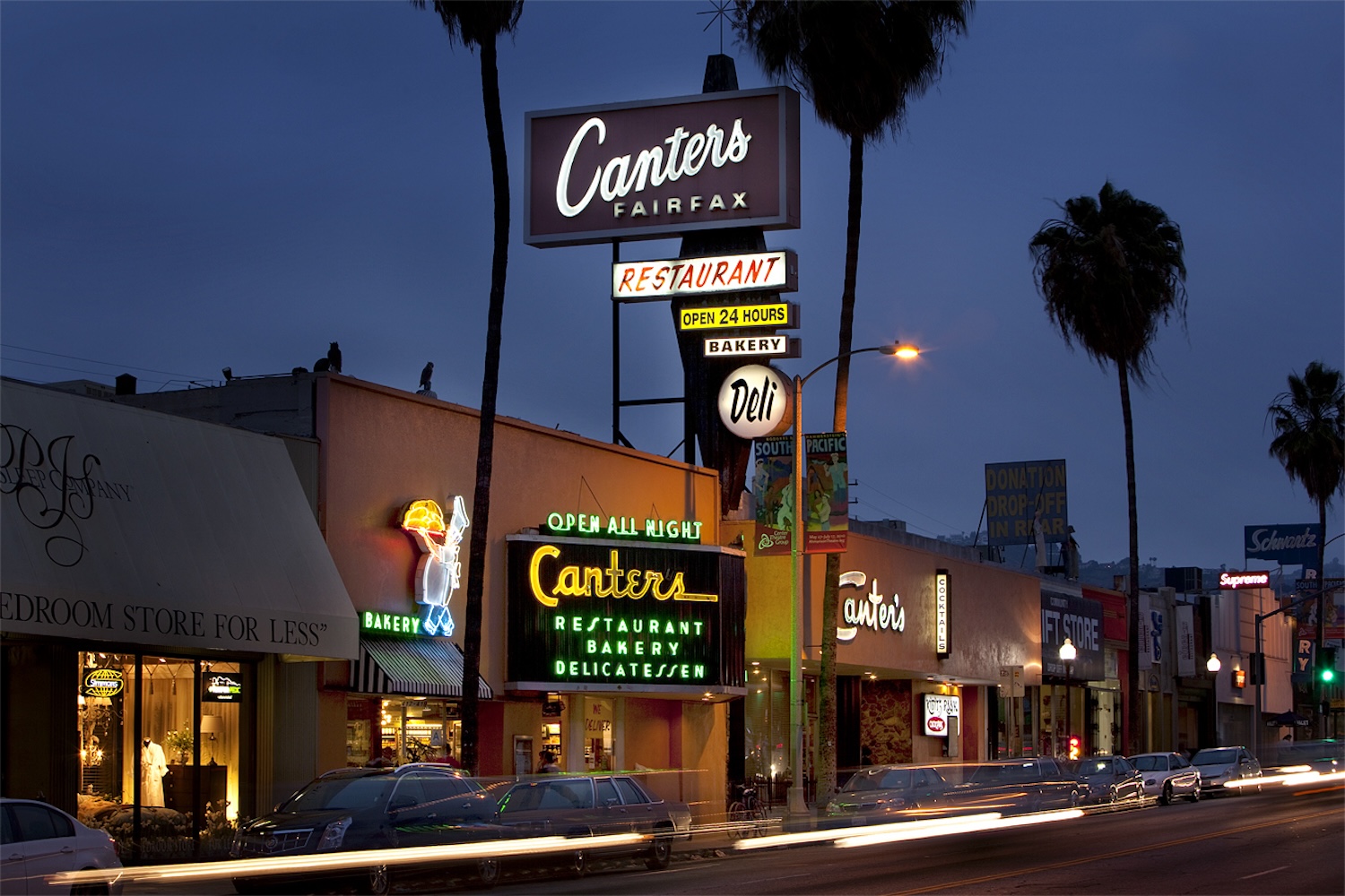 outdoor strip of restaurants, palm trees, nighttime, neon signs 