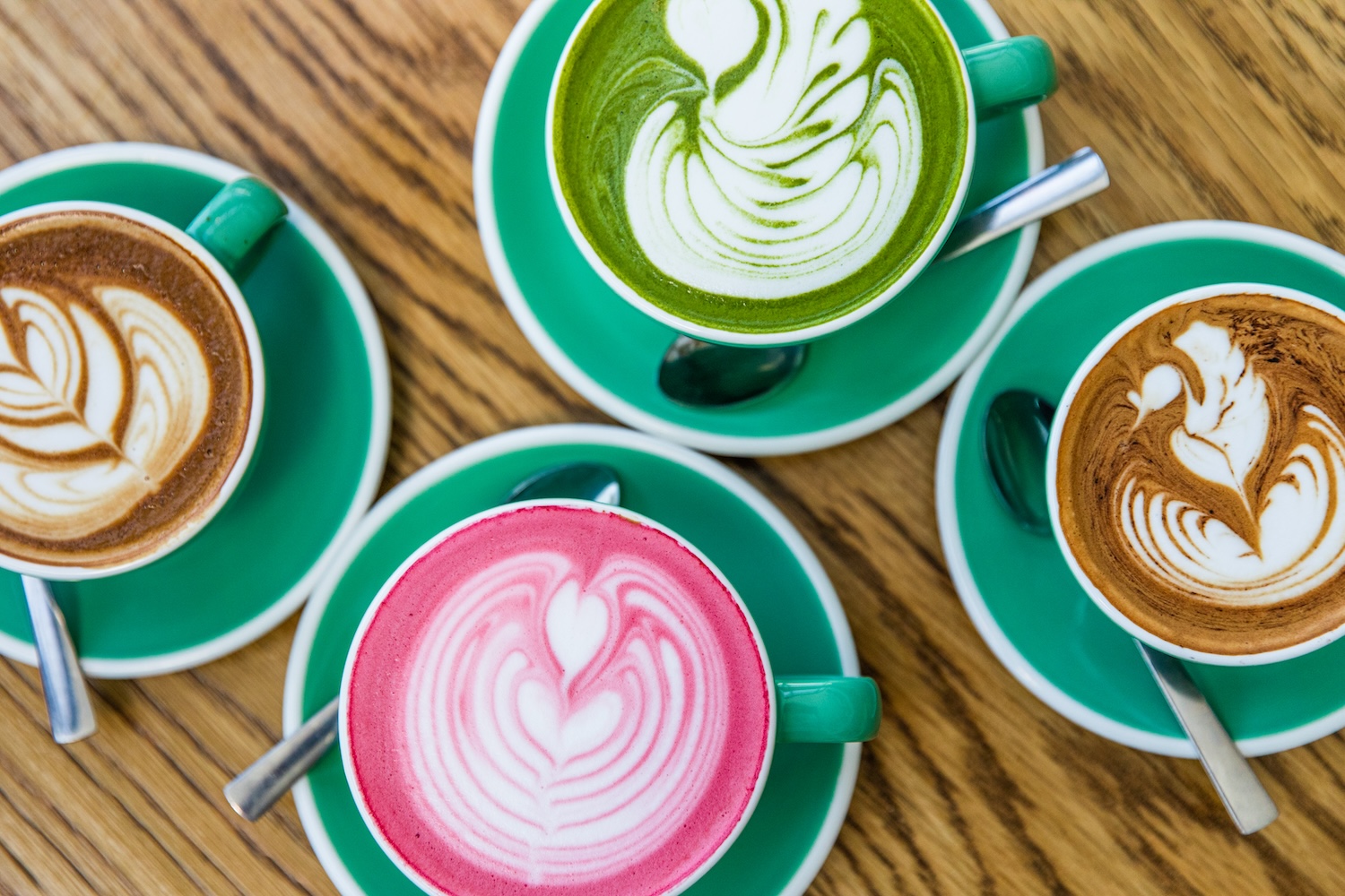 four lattes in teal cups, one green and one pink