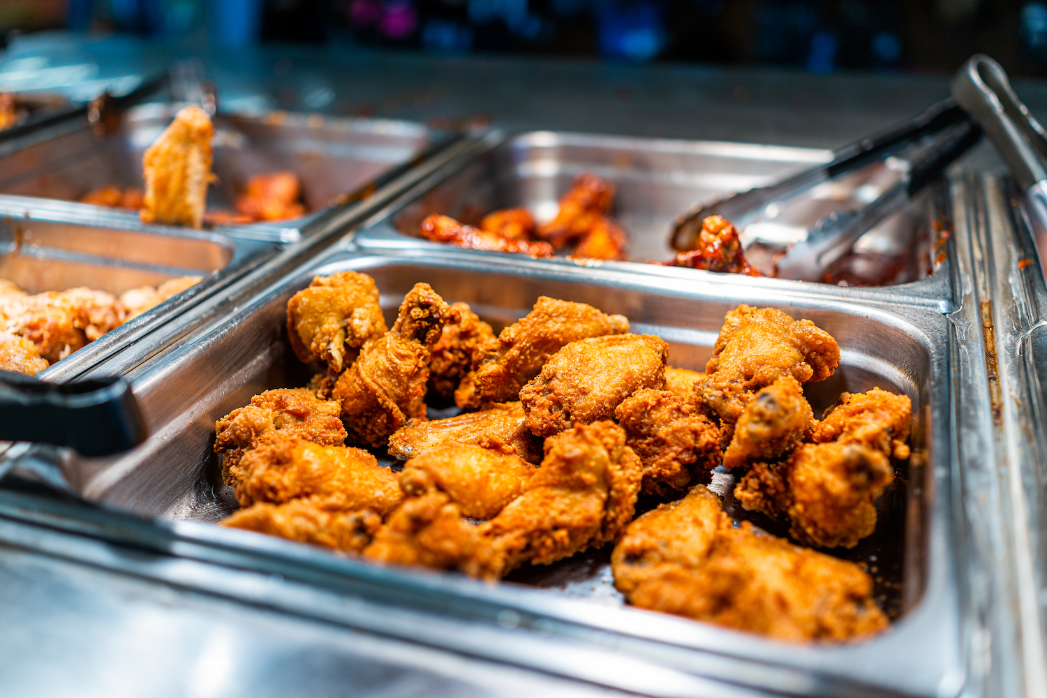 Fried chicken thighs buffet bar self serve with tongs in grocery store, restaurant or catering event with crisp skin