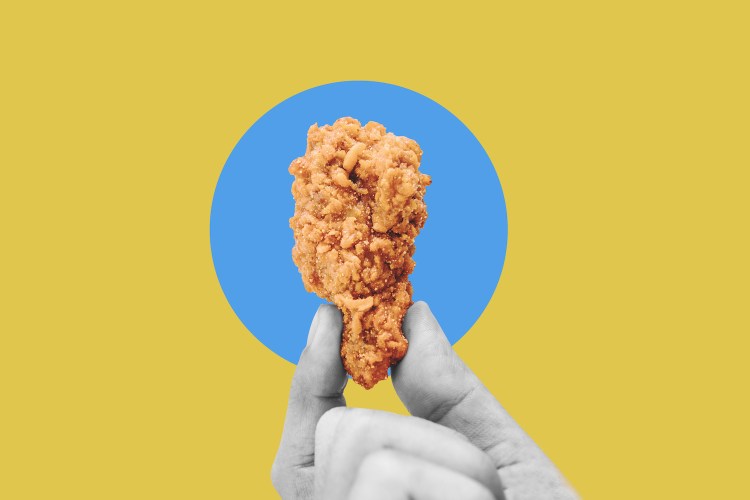 Hand holding fries chicken drumstick, on blue yellow background