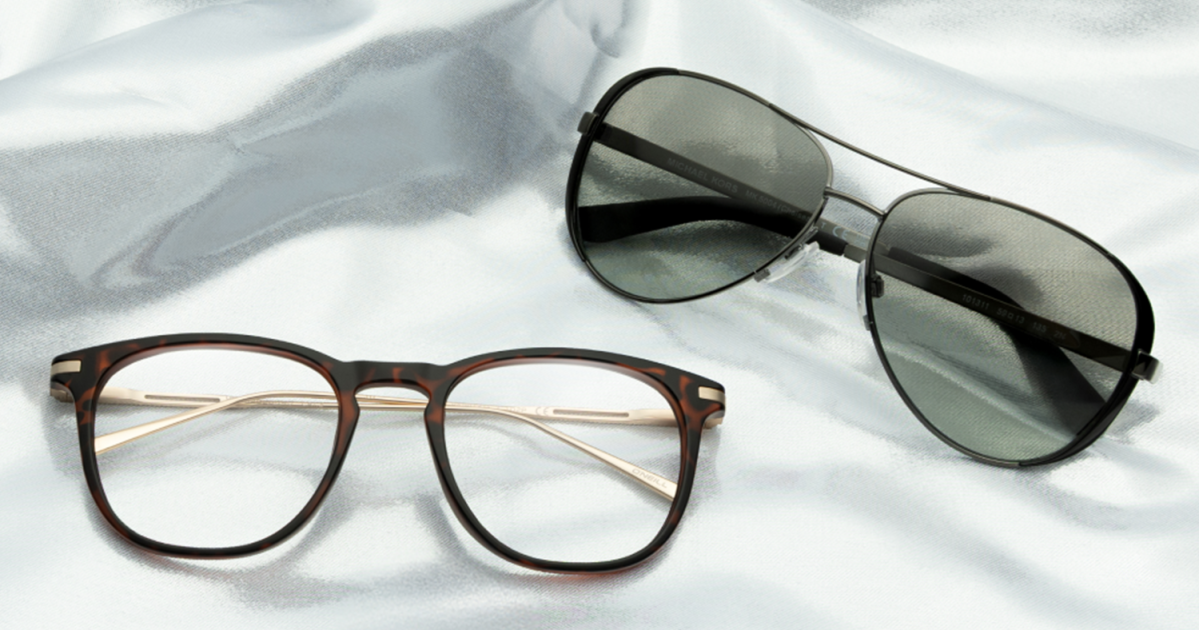A pair of sunglasses and a pair of eyeglasses sitting on a sheet
