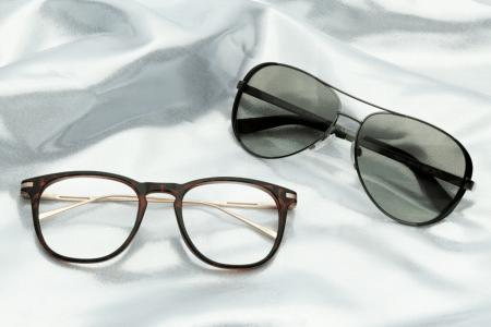 A pair of sunglasses and a pair of eyeglasses sitting on a sheet