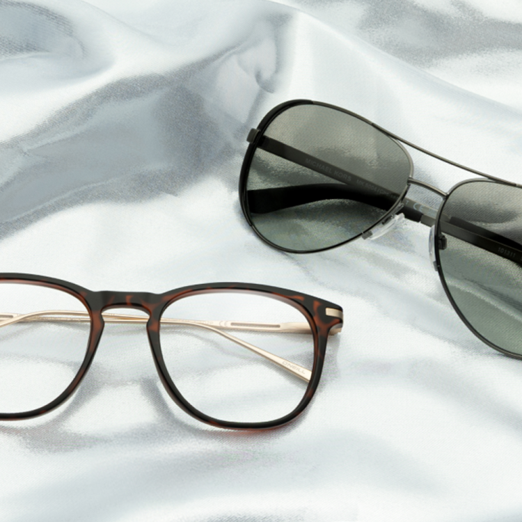 A pair of sunglasses and a pair of eyeglasses sitting on a sheet