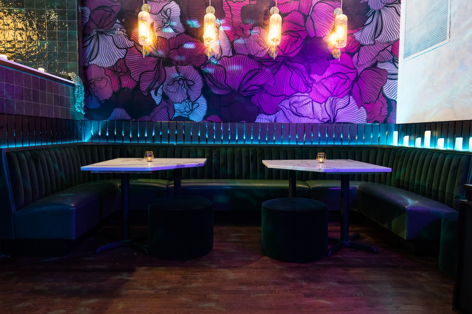 two tables with blue booth, purple flower wallpaper, lights hanging