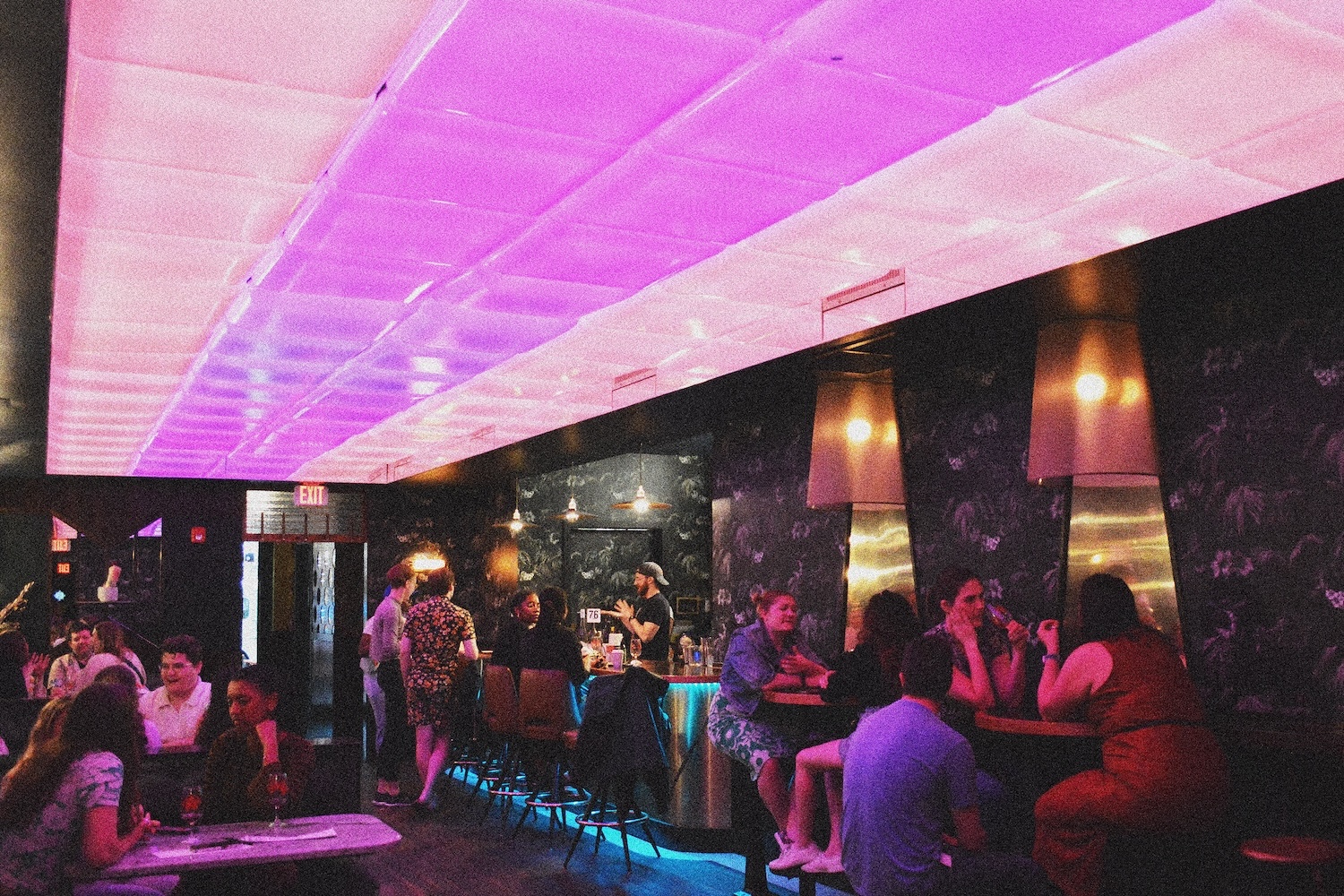 pink ceiling lights, blue floor lights, people mingling on a bar