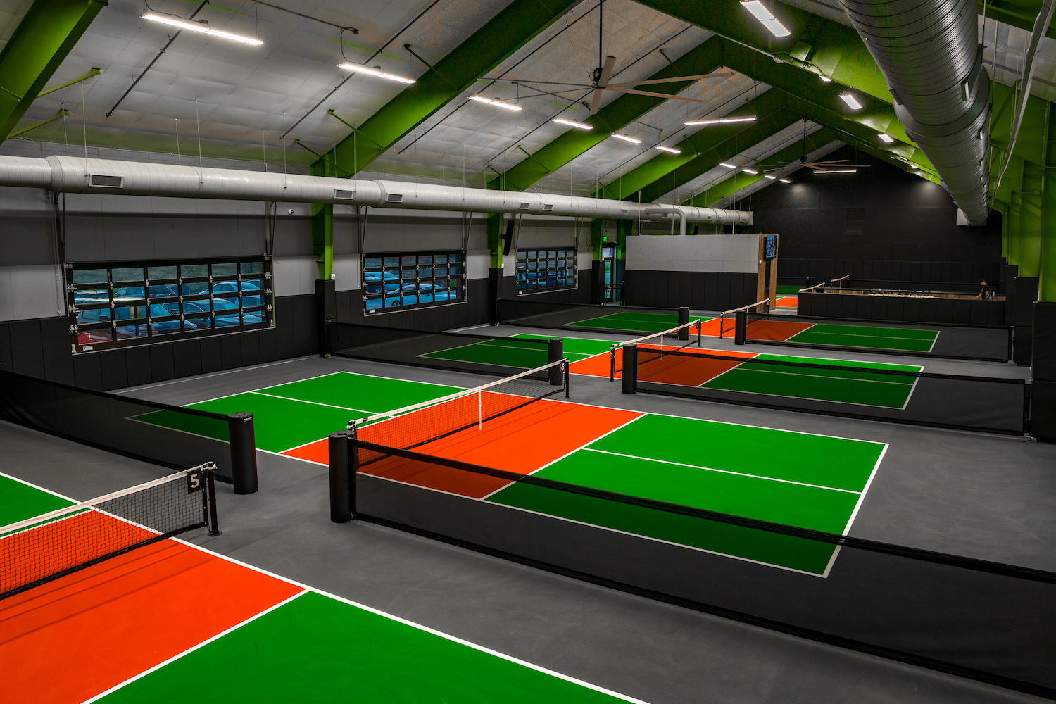 green and orange playing courts with fences and overhead lights