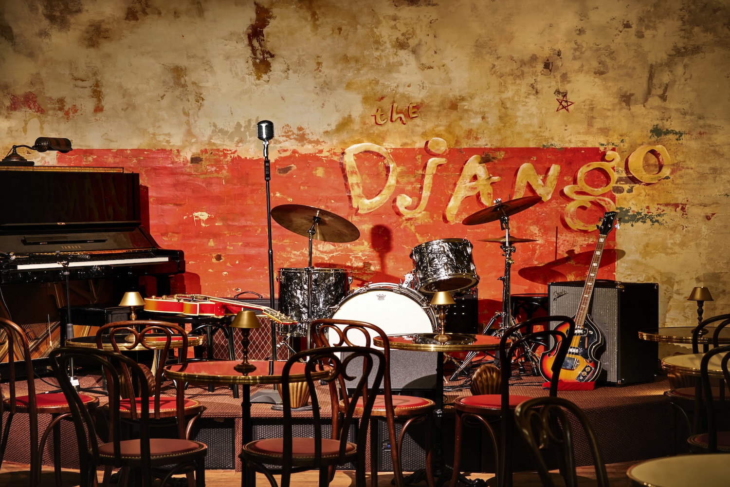 brick wall painted red with a yellow sign, drums, chairs, mic stand