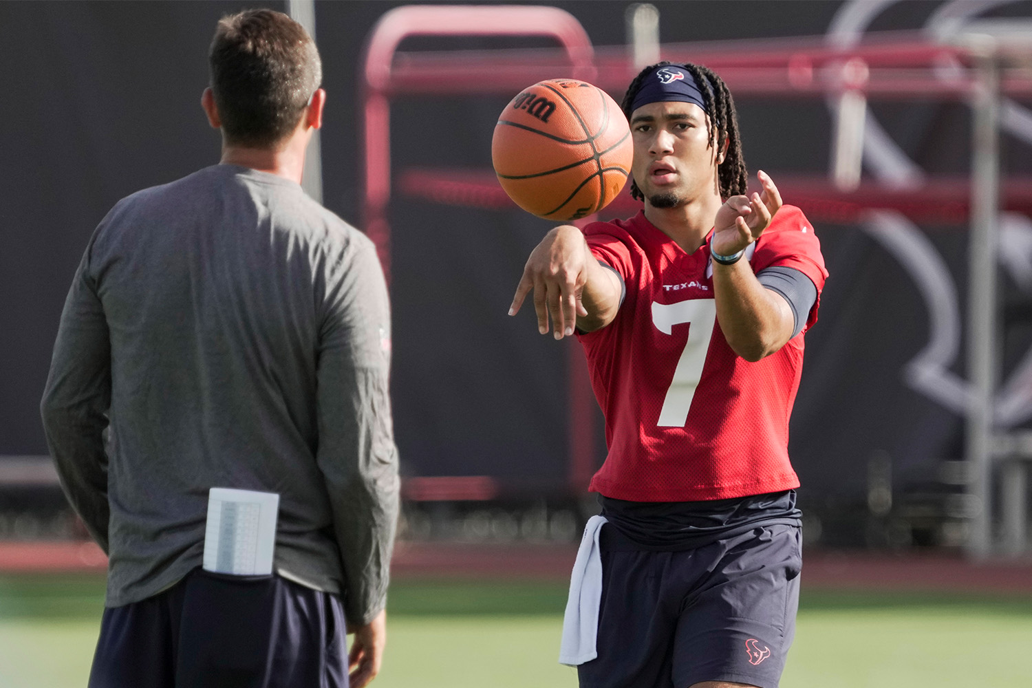 C.J. Stroud warms up by passing a basketball to his trainer.