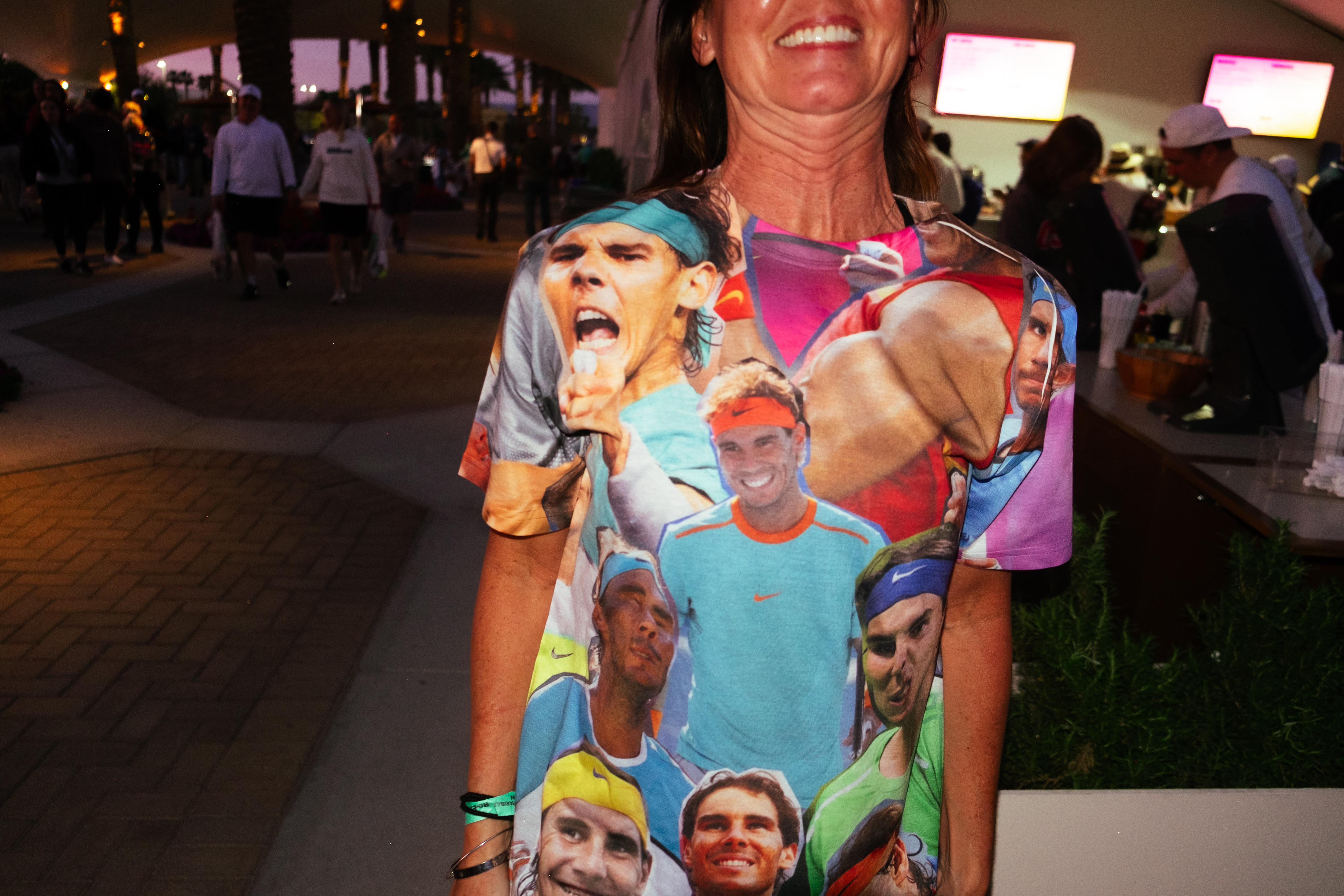 A woman wearing a Rafael Nadal shirt grins for the camera.